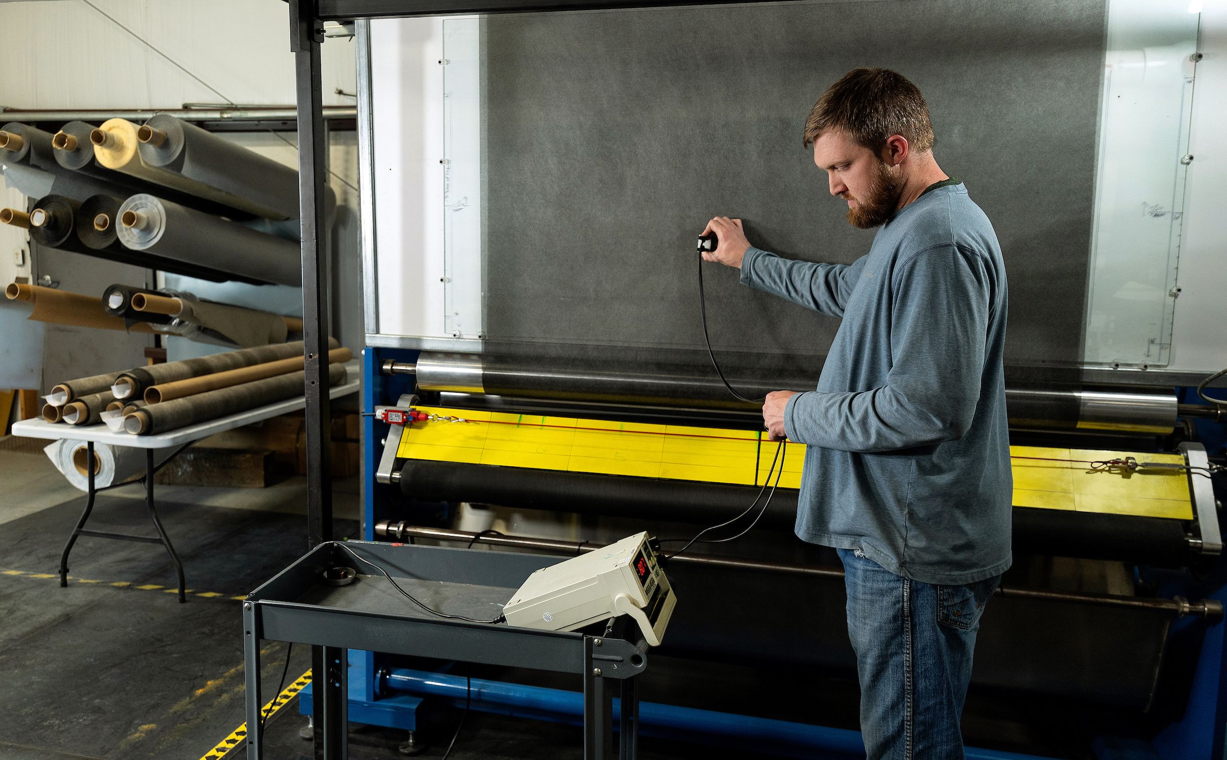 A technician measuring the surface resistance of a shielding material roll with a handheld probe